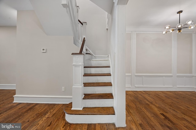 stairway with hardwood / wood-style floors and a notable chandelier