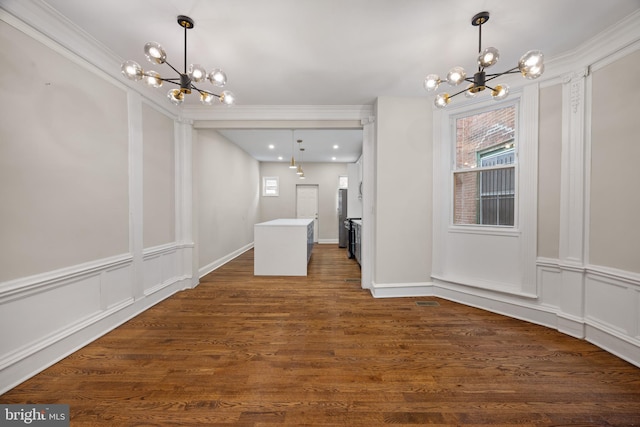 unfurnished dining area with dark hardwood / wood-style floors, crown molding, and a chandelier