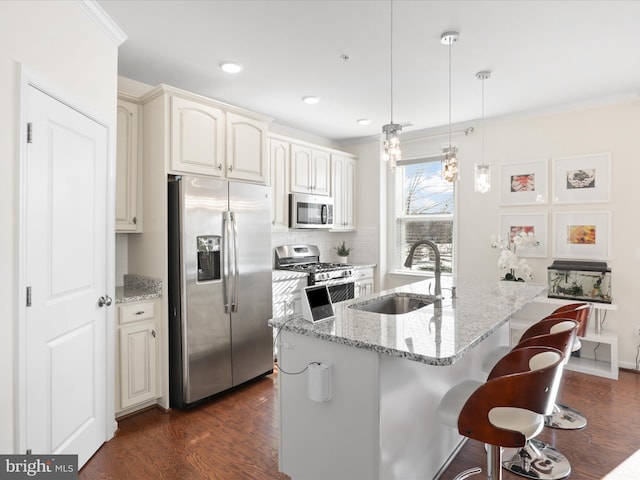 kitchen featuring sink, stainless steel appliances, decorative light fixtures, and light stone counters