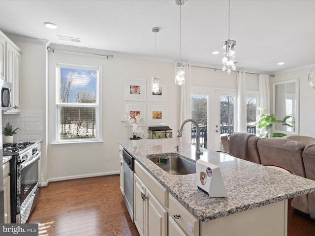 kitchen with hanging light fixtures, an island with sink, backsplash, appliances with stainless steel finishes, and sink