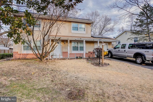 view of front of property featuring a garage, brick siding, and fence