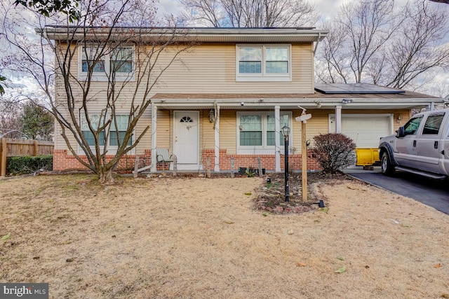 view of front of home with a garage, solar panels, brick siding, fence, and driveway