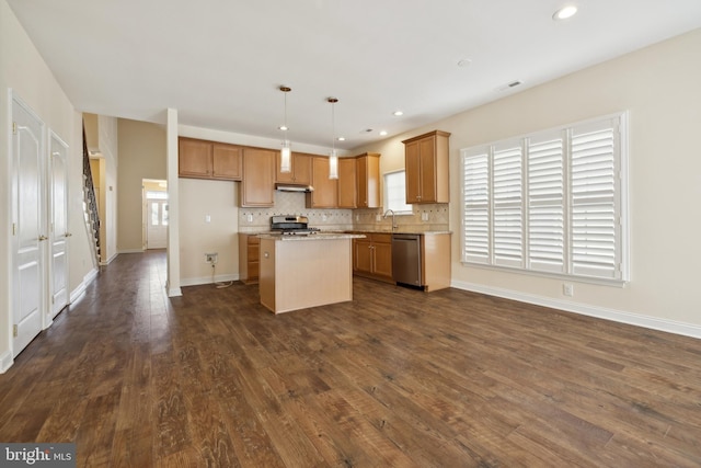 kitchen with hanging light fixtures, stainless steel appliances, a center island, light stone countertops, and dark hardwood / wood-style flooring