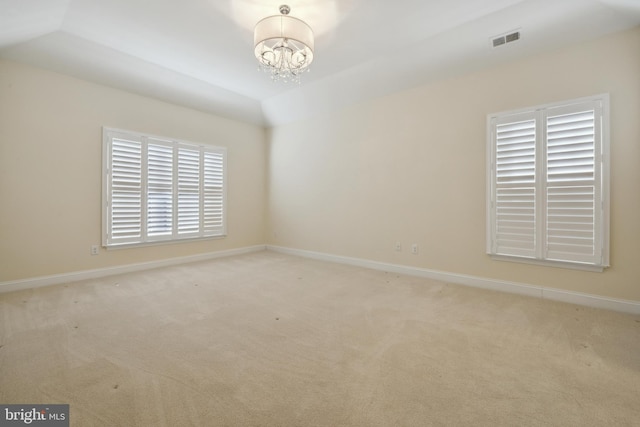 carpeted spare room with lofted ceiling and a chandelier