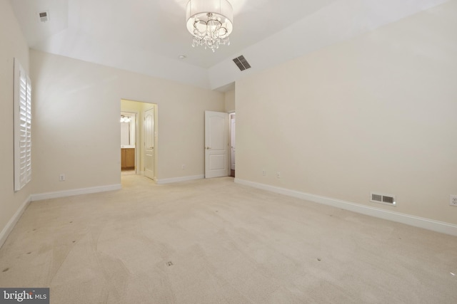 unfurnished bedroom with ensuite bath, light carpet, vaulted ceiling, and a notable chandelier