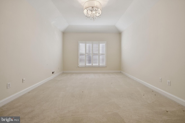 carpeted spare room featuring lofted ceiling and a chandelier