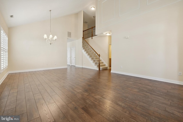 empty room with dark wood-type flooring, high vaulted ceiling, and an inviting chandelier