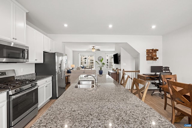 kitchen featuring sink, white cabinets, ceiling fan, stone countertops, and appliances with stainless steel finishes