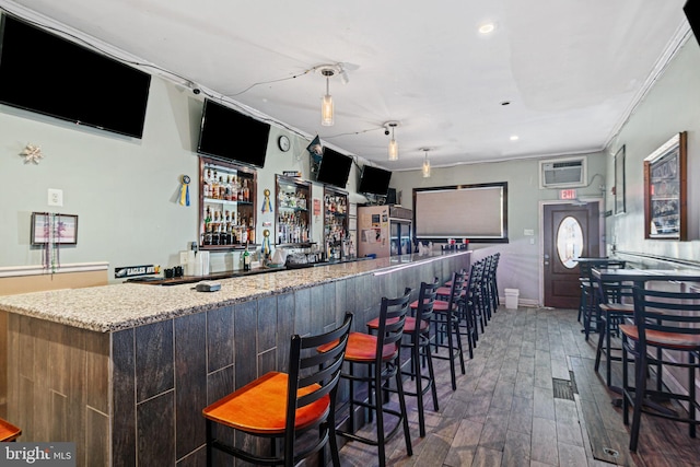 bar featuring a wall mounted air conditioner, dark hardwood / wood-style flooring, light stone counters, and ornamental molding