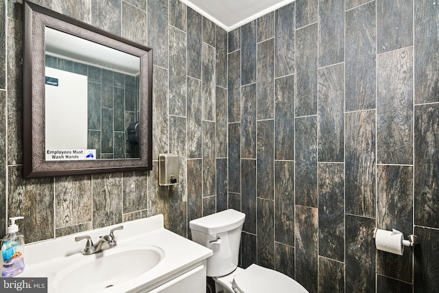 bathroom with vanity, toilet, and tile walls