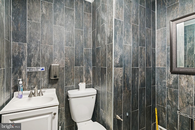 bathroom featuring vanity, tile walls, and toilet