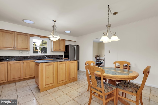 kitchen featuring decorative light fixtures, black refrigerator, sink, and a kitchen island