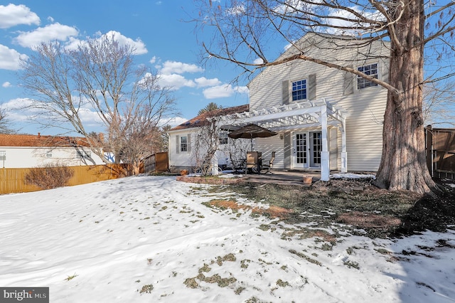 snow covered back of property with a pergola