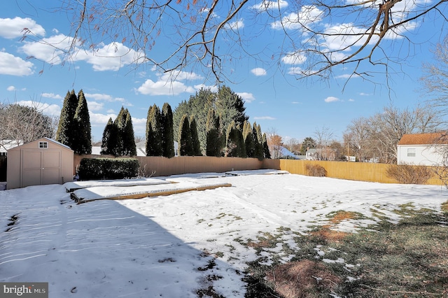 yard layered in snow featuring a storage unit