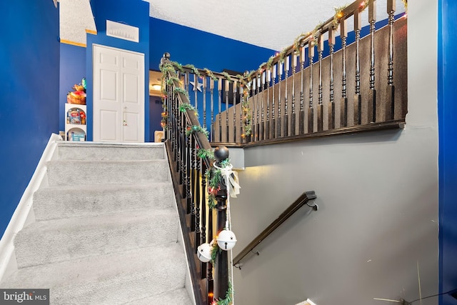 stairway featuring a textured ceiling