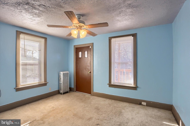 carpeted spare room featuring radiator heating unit, a textured ceiling, and ceiling fan