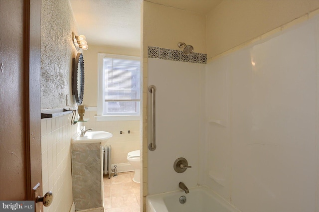 full bathroom featuring radiator, tile patterned floors,  shower combination, toilet, and tile walls