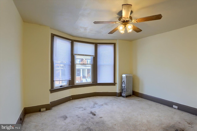 empty room featuring radiator, ceiling fan, and light colored carpet