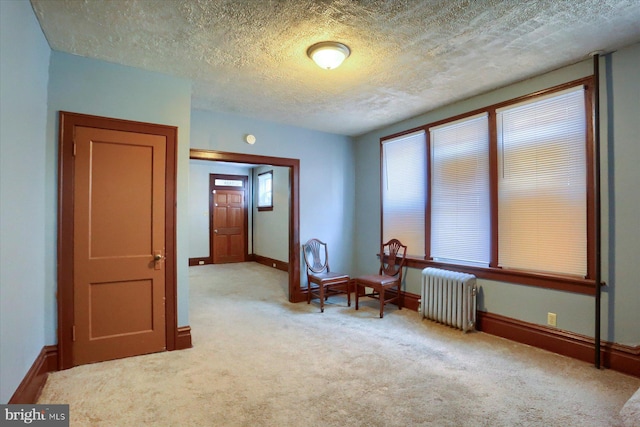 unfurnished room featuring a textured ceiling, light carpet, and radiator