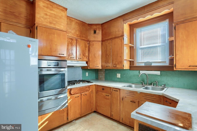 kitchen featuring a textured ceiling, white appliances, backsplash, and sink