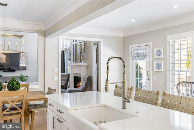 kitchen featuring white cabinetry, crown molding, pendant lighting, and sink