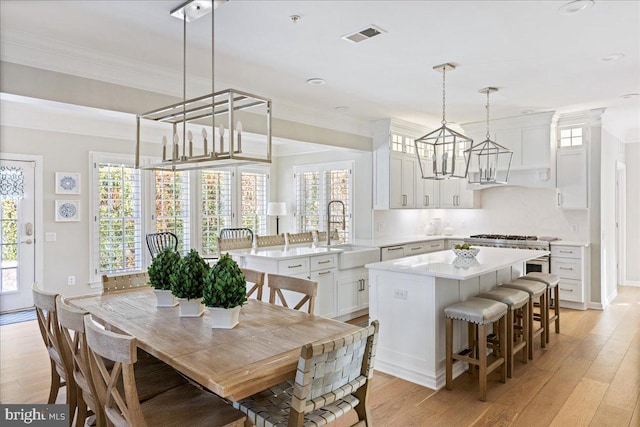 dining space featuring ornamental molding, light hardwood / wood-style flooring, and sink