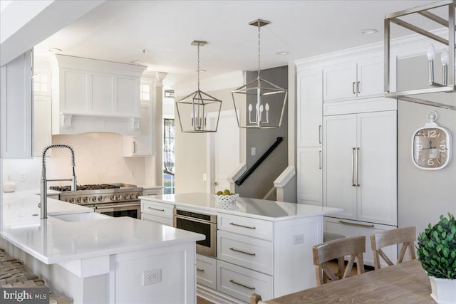 kitchen with paneled built in fridge, a breakfast bar area, a center island, stainless steel oven, and white cabinetry