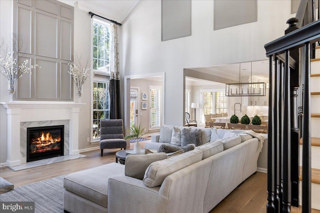 living room featuring a high ceiling, a premium fireplace, ornamental molding, and hardwood / wood-style flooring