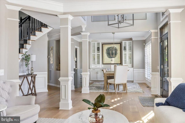 living room featuring light wood-type flooring, crown molding, and a notable chandelier