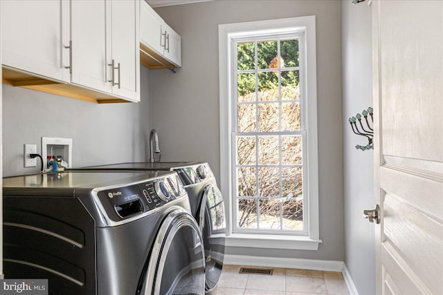 washroom with light tile patterned flooring, washing machine and clothes dryer, and cabinets