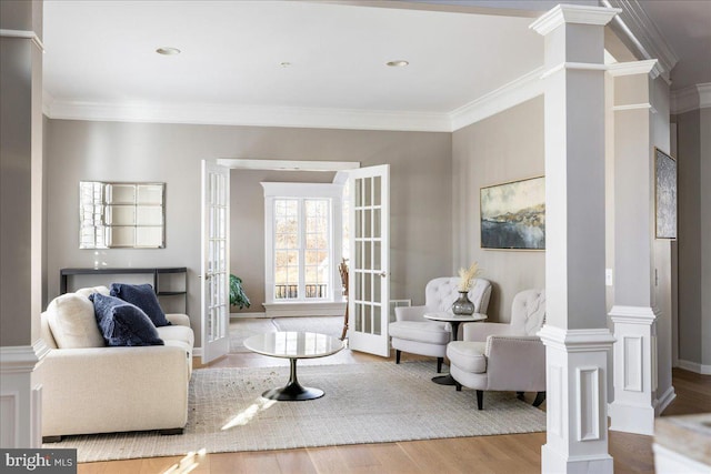 living room featuring french doors, ornamental molding, light hardwood / wood-style floors, and decorative columns