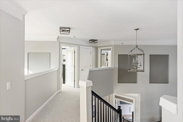 corridor featuring light colored carpet, crown molding, and a chandelier