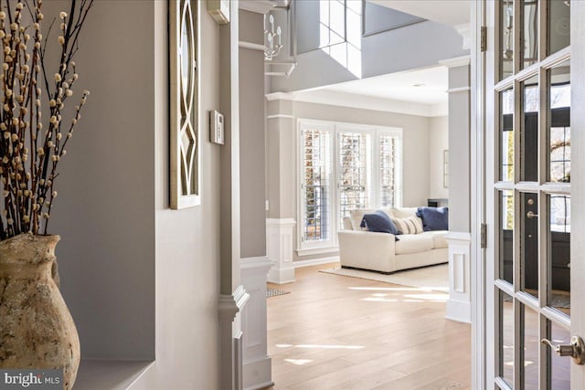 hallway featuring decorative columns, light hardwood / wood-style floors, and crown molding