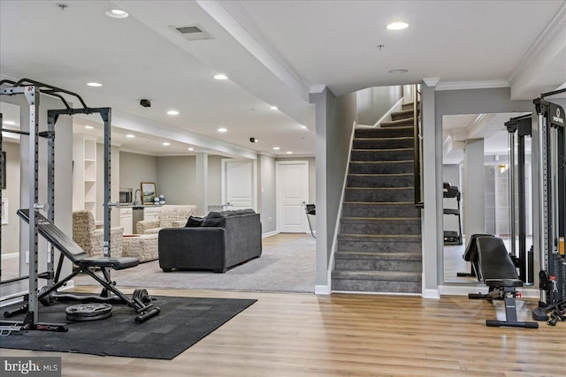 exercise room with light wood-type flooring and crown molding