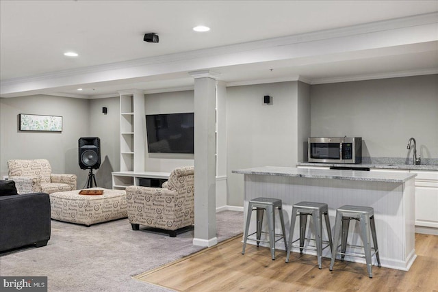 living room featuring ornamental molding, light hardwood / wood-style floors, and sink