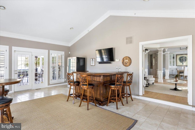 bar featuring crown molding, high vaulted ceiling, decorative columns, and light tile patterned floors