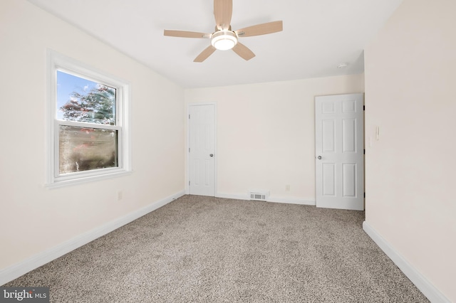 spare room with carpet floors, baseboards, visible vents, and a ceiling fan