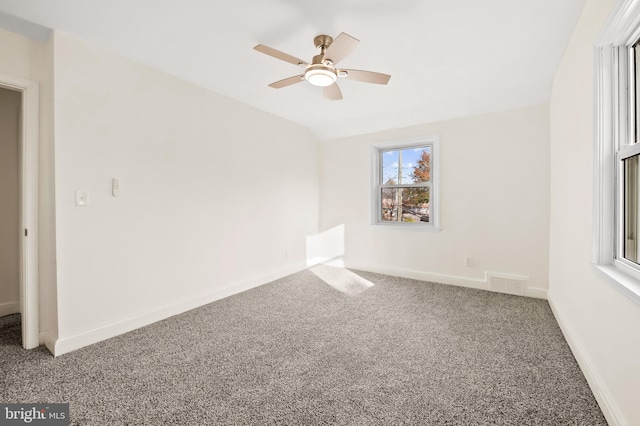 carpeted empty room featuring lofted ceiling, visible vents, ceiling fan, and baseboards