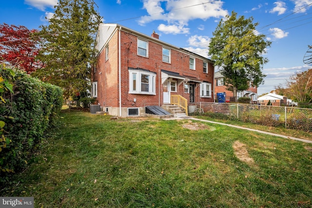 view of front of home featuring brick siding, a chimney, a front yard, central AC, and fence