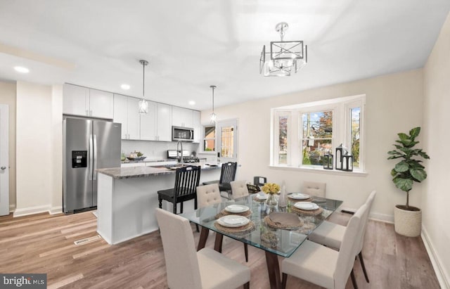 dining space with baseboards, an inviting chandelier, light wood-style flooring, and recessed lighting