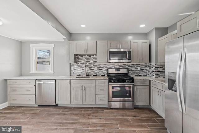 kitchen featuring appliances with stainless steel finishes, wood-type flooring, tasteful backsplash, sink, and gray cabinets