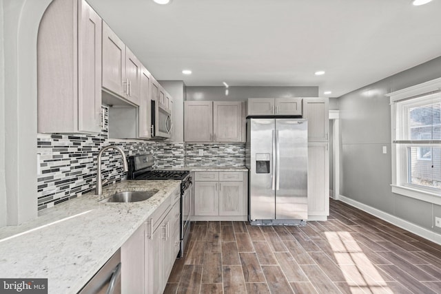 kitchen with light stone countertops, decorative backsplash, appliances with stainless steel finishes, and sink