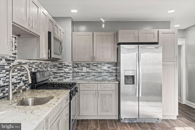 kitchen with light stone countertops, stainless steel appliances, decorative backsplash, and sink