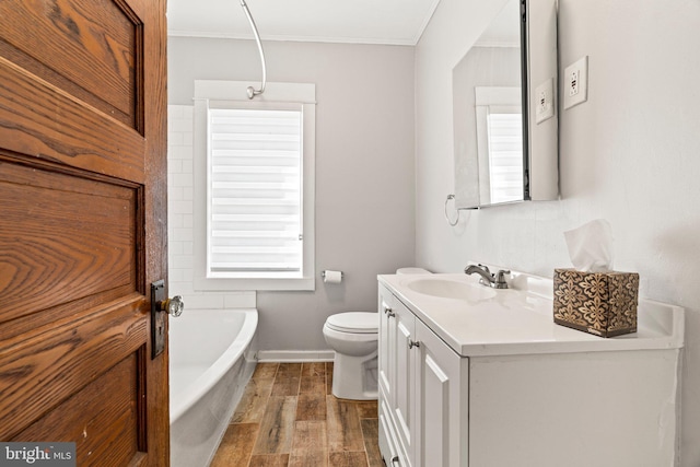 bathroom featuring crown molding, vanity, toilet, and a washtub