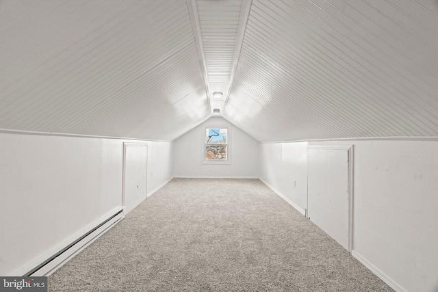 additional living space with a baseboard heating unit, vaulted ceiling, and light carpet