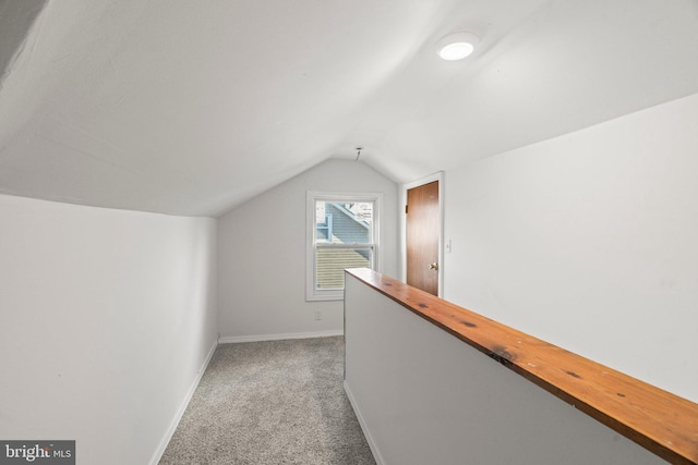 hallway featuring vaulted ceiling and light carpet