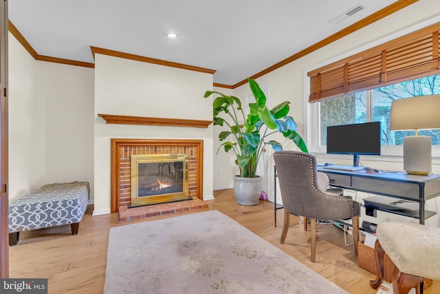 home office with light wood-type flooring, crown molding, and a fireplace