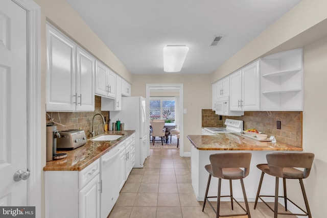 kitchen featuring backsplash, sink, white appliances, white cabinetry, and light tile patterned flooring