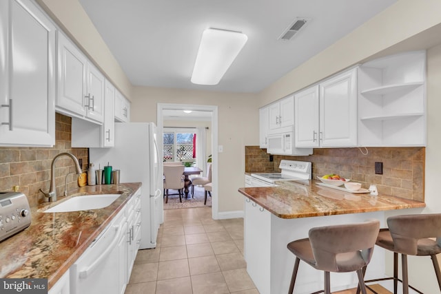 kitchen featuring a kitchen breakfast bar, sink, white appliances, and white cabinetry