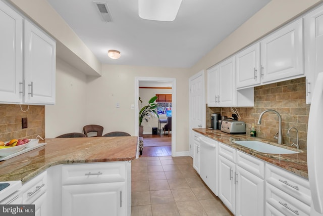 kitchen with white cabinets, light stone counters, sink, and light tile patterned floors